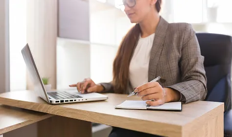 Profesional en un escritorio, trabajando con laptop y cuaderno